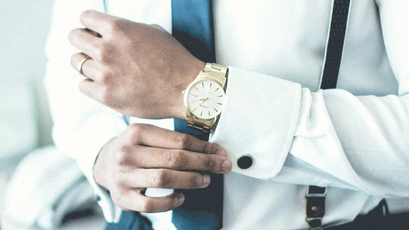 Un directivo se ajusta el puño de la camisa, con gemelo y reloj de oro