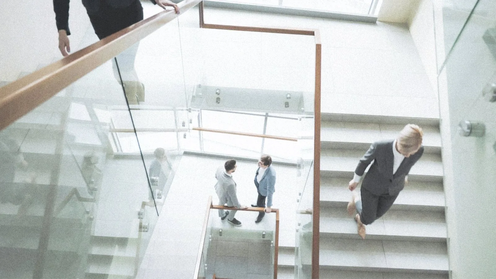 Directivos cruzándose en la escalera de vidrio de un atrio luminoso